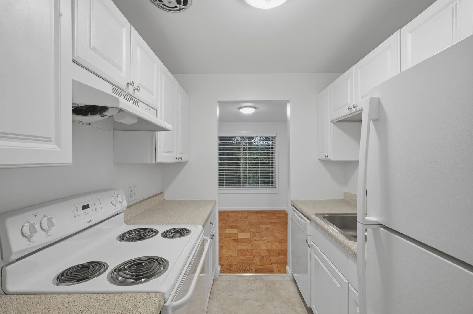 Galley kitchen with white cabinets and electric range